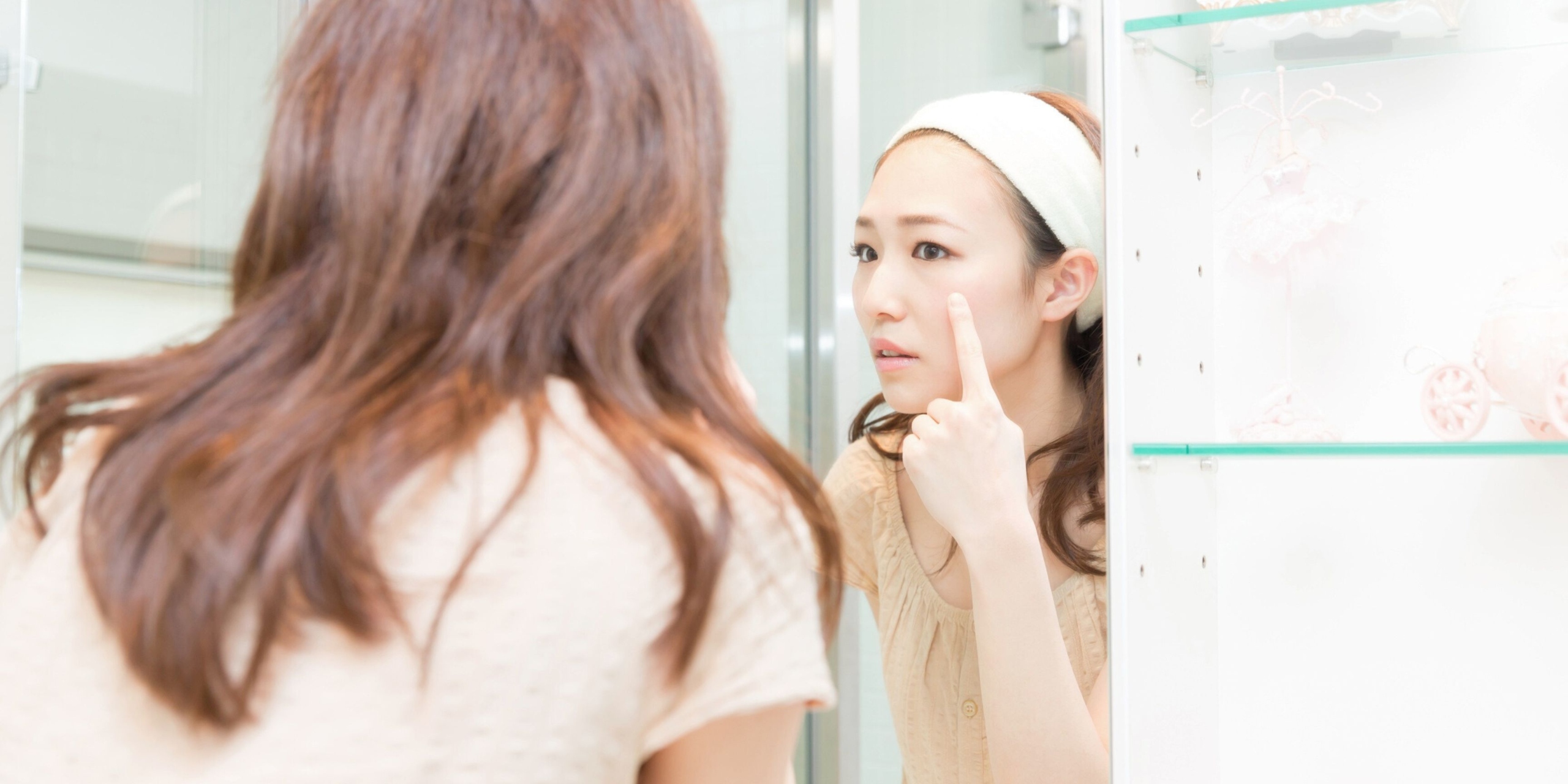Woman looking at her face in the bathroom mirror